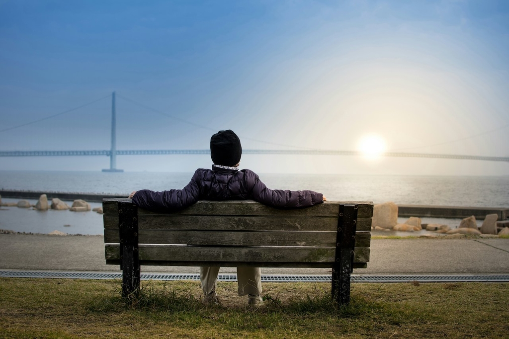 Personne assise sur un banc regardant la mer